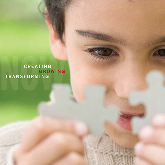 A young student focussing intently on puzzle pieces and smiling with the title Now Creating Growing Transforming