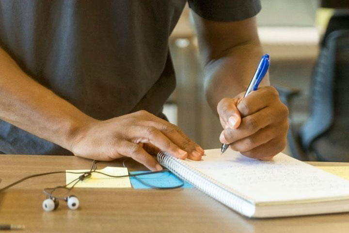 A student taking notes in a spiral notebook