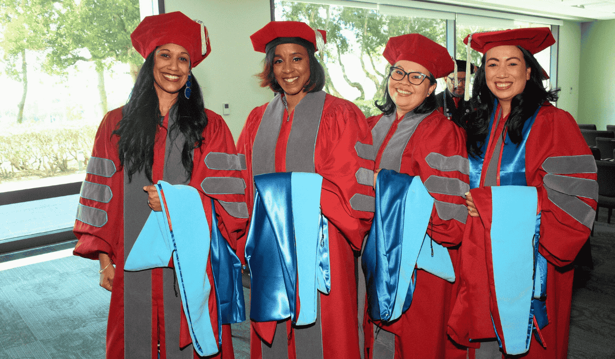 four women dressed in graduate commencement regalia