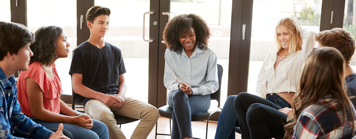 counselor sitting with a group of teenagers