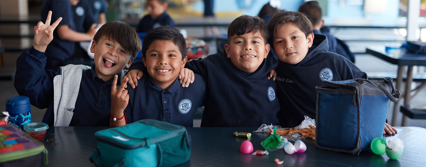 four Catholic school boys sitting at a lunch table