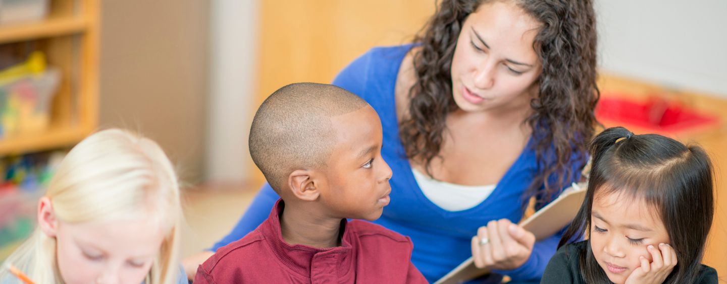 Teacher working with three students at a table