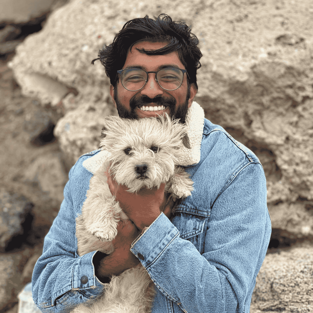 a man standing outdoors holding a white dog