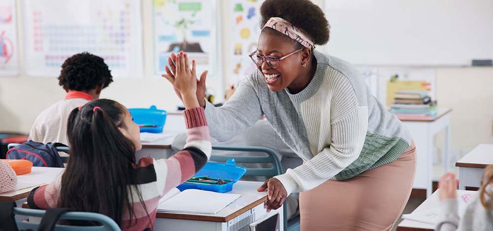 teacher giving student a high five in a classroom