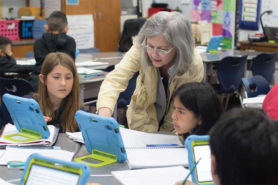 A teacher pointing to something on an ipad