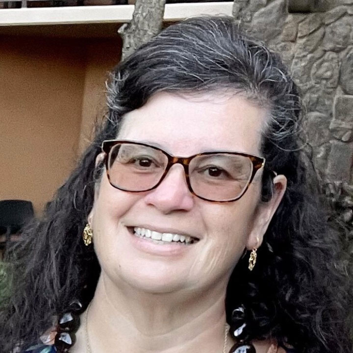 headshot of a woman leaning against a tree