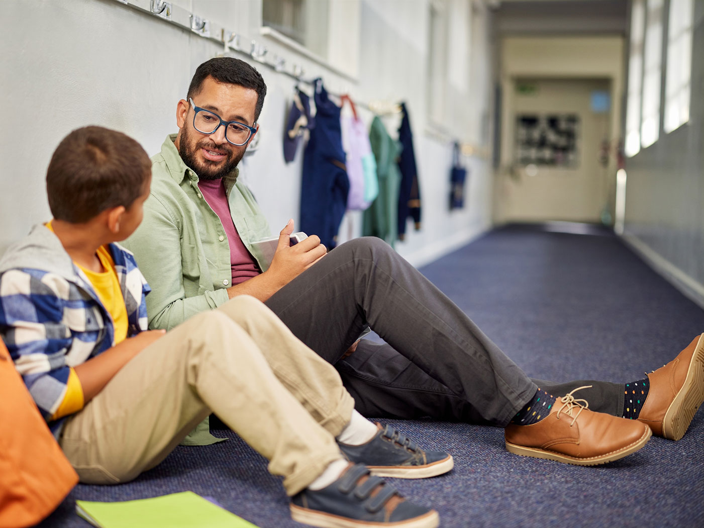 student and teacher seated in a hallway talking to each other