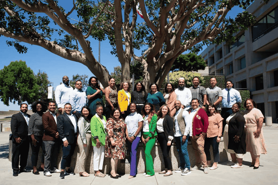 Group of graduate students standing in front of a tree outside