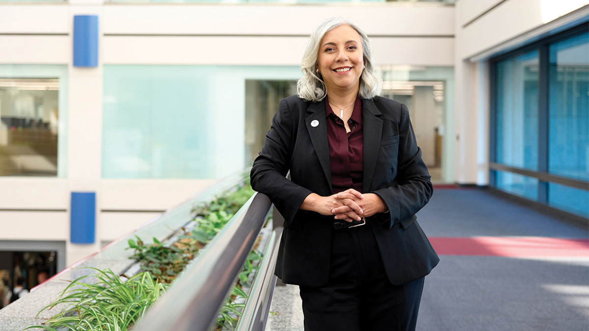 A Gray Haired woman poses next to a gray railing