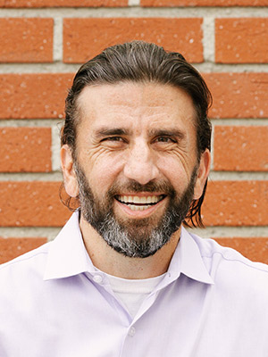 Andrew Furedi portrait man in front of orange brick wall