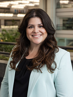 Woman with brown hair in teal blazer posing
