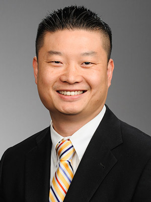 Tommy Chang portrait of a dark haired man in black suit