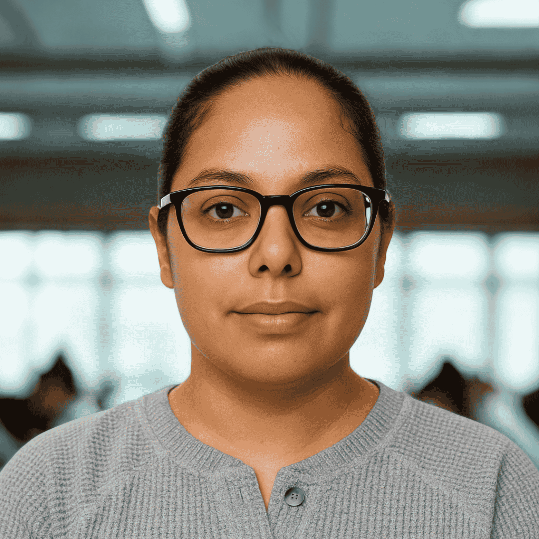 headshot of a woman wearing glasses and standing in a classroom
