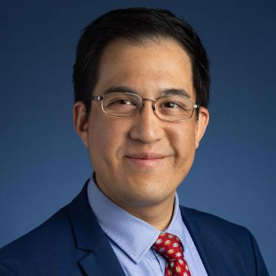 man wearing a blue suit and shirt and tie against a blue background