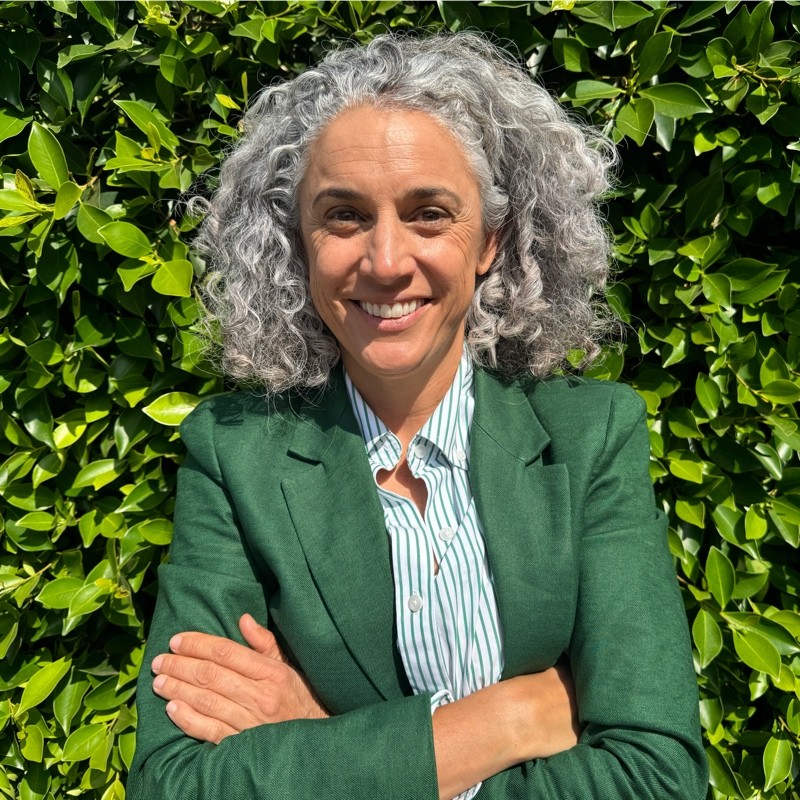 Headshot of a woman against a greenery wall