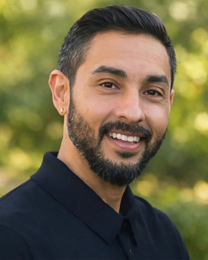 Fernando Estrada wearing black, posing outside with a green background
