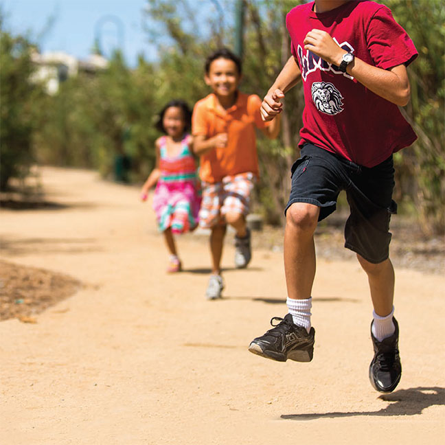 Children wearing LMU branded clothes running through Ballona Discovery Park with the title Trailblazers Leading the Way in Education