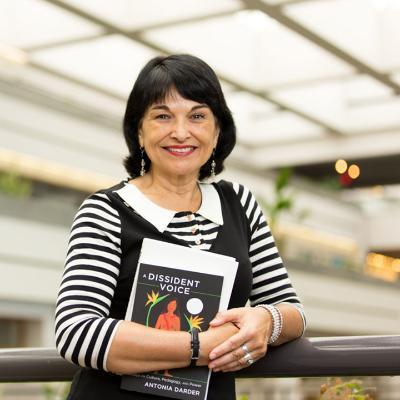 Picture of SOE professor Antonia Darder holding her book in LMU's University Hall
