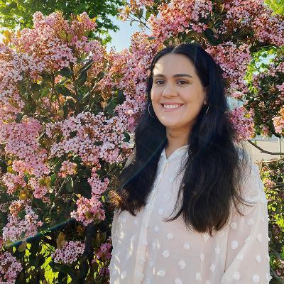 UB and SOE alumna Fatima Galvez standing in front of a pink flowering shrub