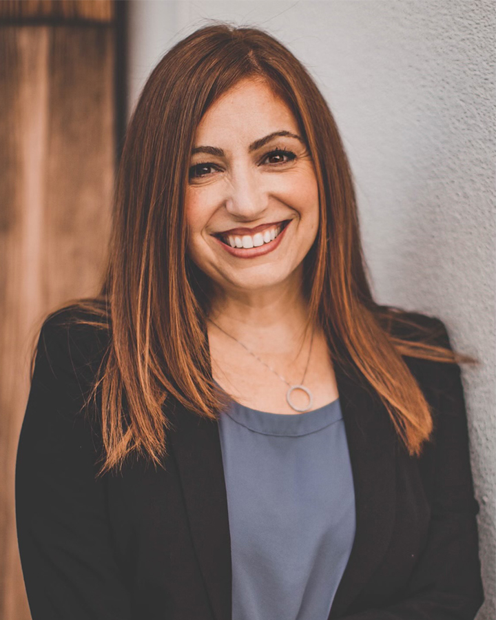 Virginia Castro Portrait leaning on a wall, wooden door behind them